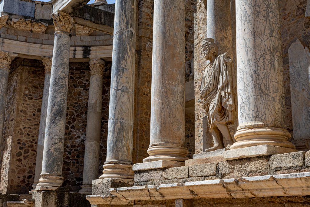 A statue of a Roman god stands amid the columns in the Roman theater.