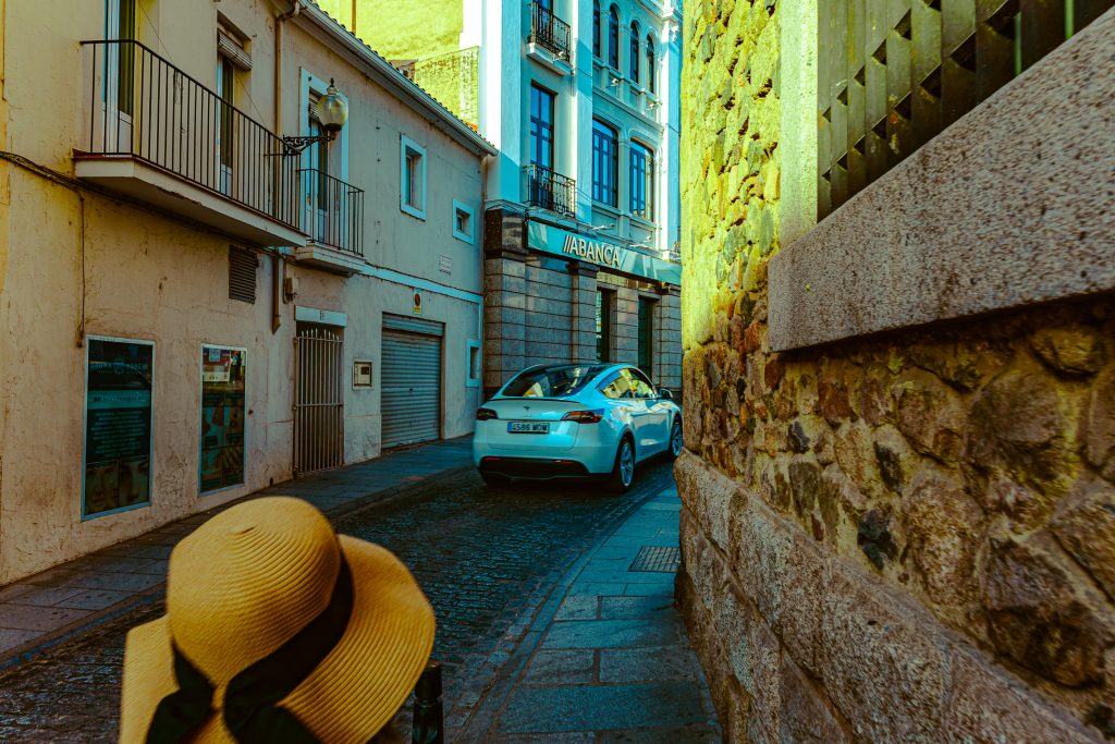 A Tesla drives by a pedestrian in the narrow streets of Mérida, Spain.